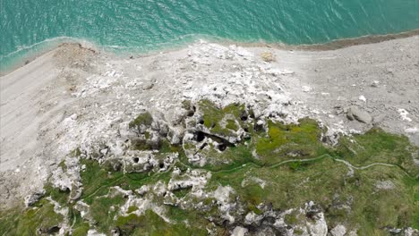 aerial view of rocky coastline with turquoise water and mossy patches