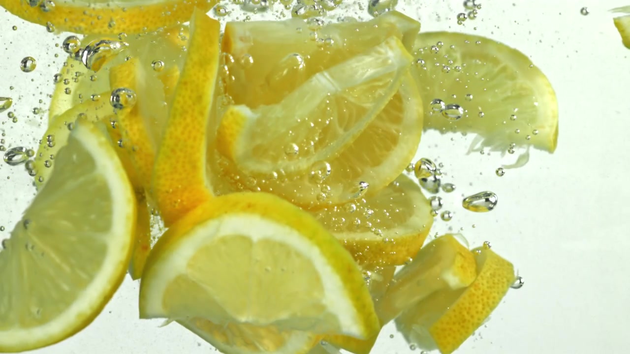 Fette di limone fresche che si tuffano in acqua limpida con bolle