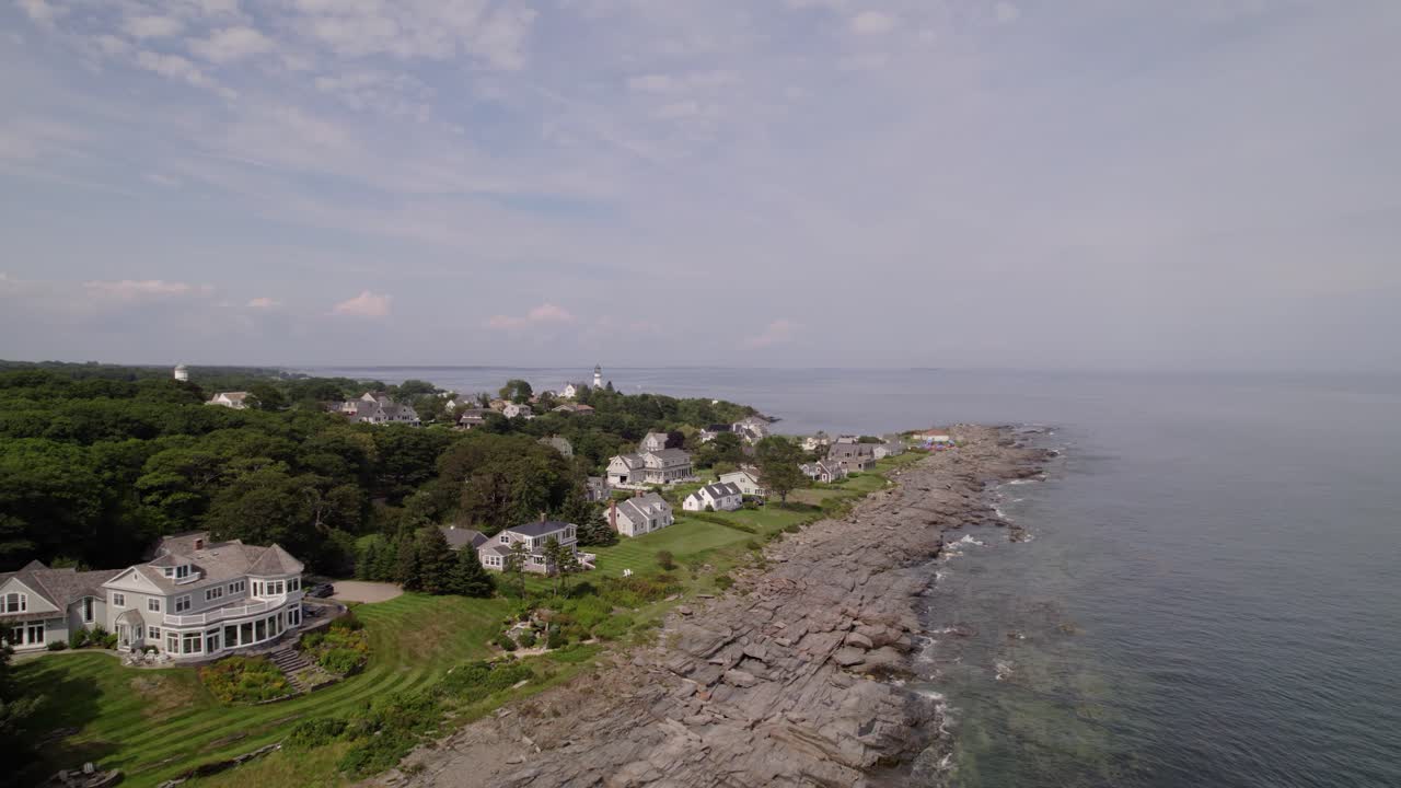 Oceanfront homes and a lighthouse along a rocky shoreline in Two Lights State Park