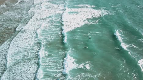 Surfer-Schwimmen-Durch-Brechende-Wellen.-Weitwinkel-Drohnenaufnahme