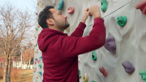 sporty man climber climbs a climbing wall - close-up