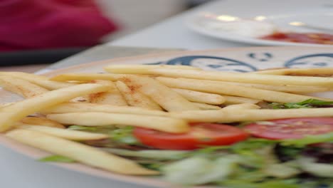 primer plano de papas fritas, tomates y lechuga en un plato