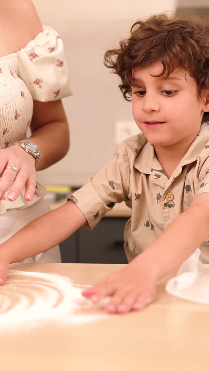 Child learning to knead dough with mother's help