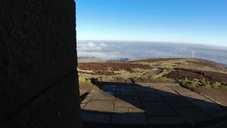 Stone-monument-doorway-viewpoint-swirling-clouds-passing-farmland-moorland-countryside-timelapse-on-bright-sunny-day