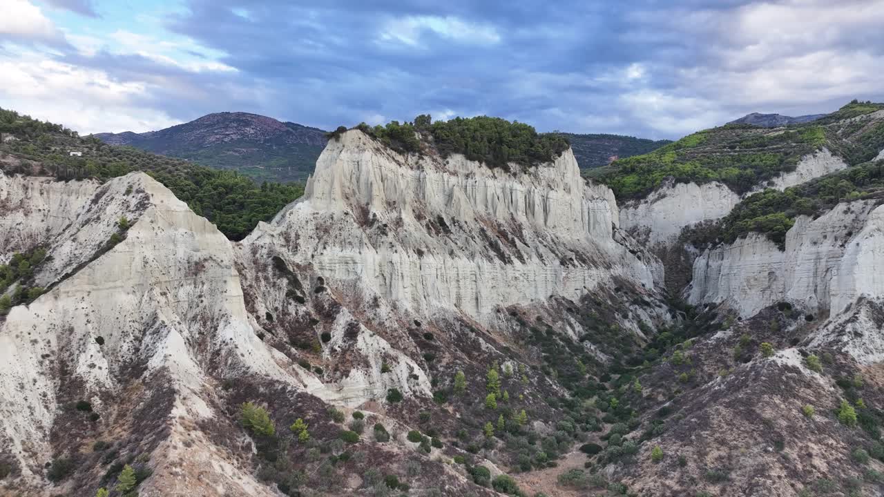 Dramatic sky and sunset off the coast of Corinth in Greece white large cliffs and lush greenery AERIAL TRUCKING LEFT PAN RIGHT