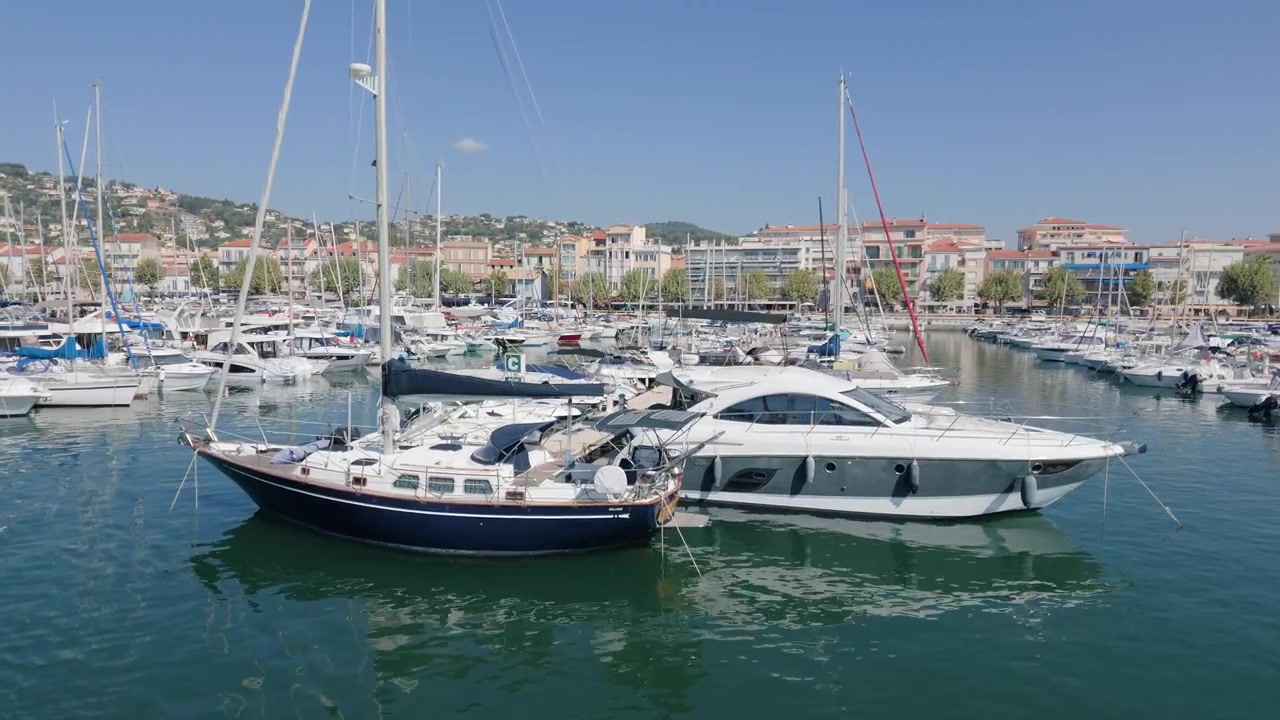 Ampia vista di yacht e barche a vela ormeggiati in un porto turistico sotto una cittadina collinare, Golfe-Juan, Francia