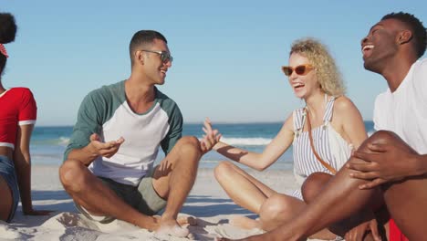 jóvenes amigos adultos sentados en una playa hablando 4k