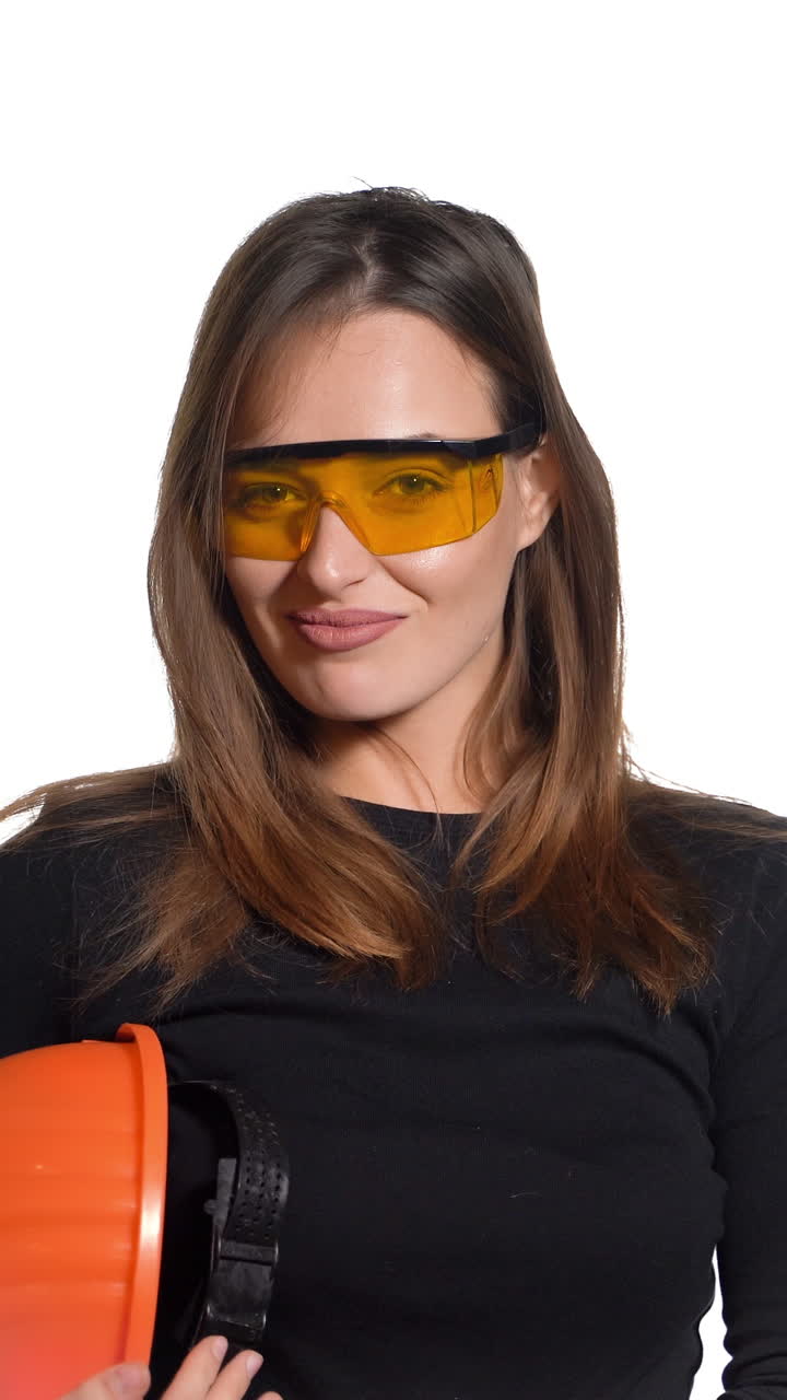 Female construction worker. Woman wearing protective helmet. Positive human emotions. Attractive young girl on white background. Vertical video