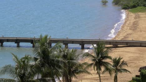 Una-Bahía-Insular,-Palmeras-Y-Un-Muelle-Con-Cultivos-De-Olas-Pequeñas