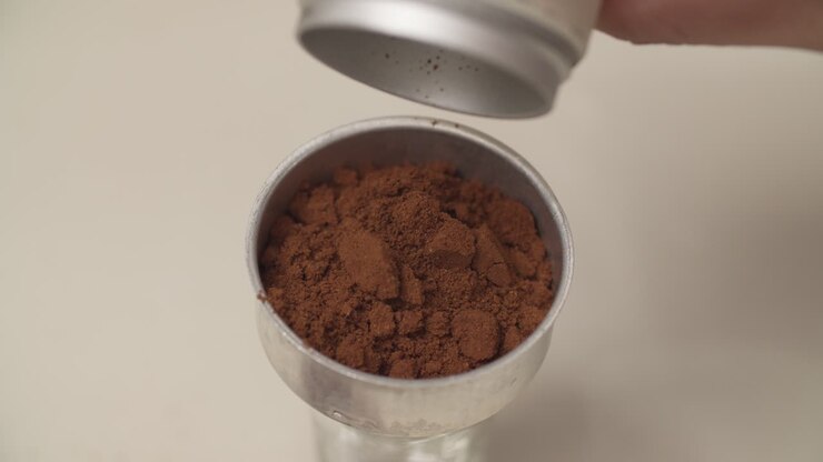 Versare fondi di caffè in un contenitore per la preparazione. Primo piano