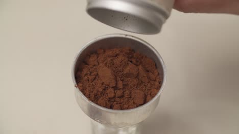 pouring coffee grounds into container for brewing. closeup shot