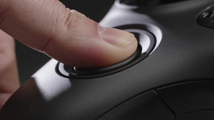 Pollice che preme entrando a sinistra, testando la risposta del joystick analogico sinistro su un gamepad nero e tornando indietro