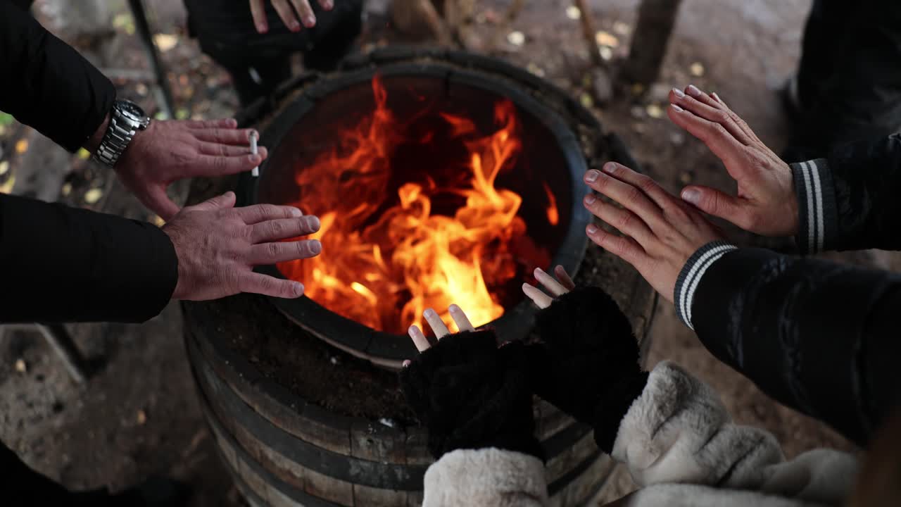 Persone che si scaldano le mani vicino a un barile infuocato