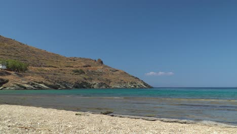 Static-view-over-rocky-beach,-ocean-and-hills-with-in-the-background