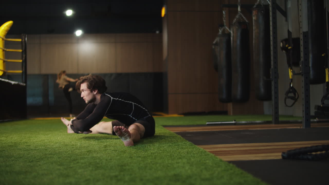 hombre en forma haciendo splits en el gimnasio. boxeador masculino haciendo estiramientos en el club deportivo