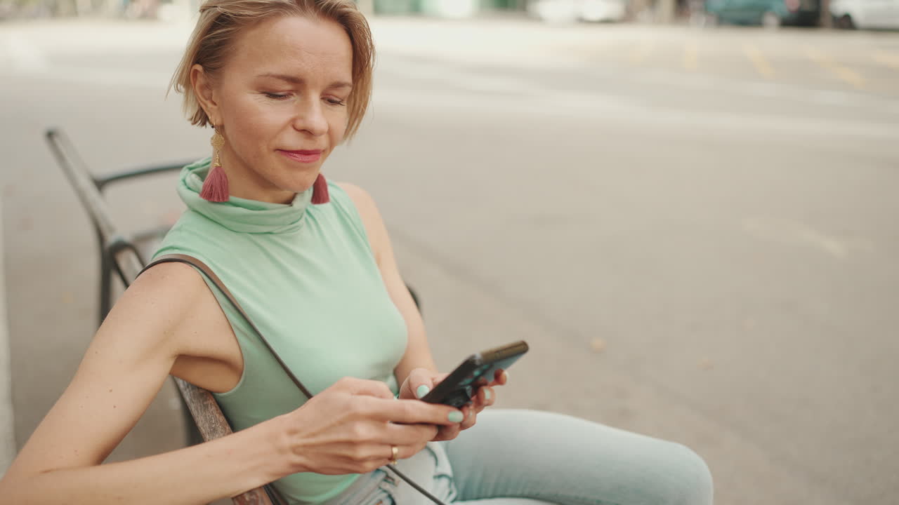 Uma mulher sentada em um banco usando um celular