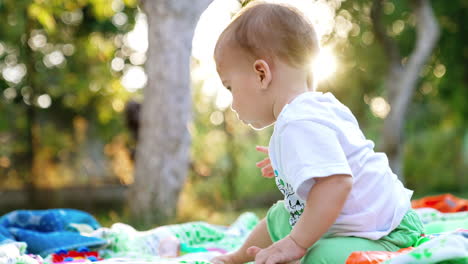 nice little boy sitting on the blankets on the ground. adorable child in the garden resting. low angle view. blurred backdrop.