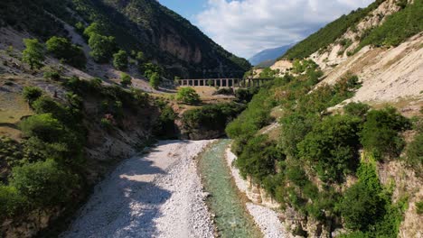 valle del río y antiguo acueducto rodeado de montañas rocosas y exuberante vegetación en albania