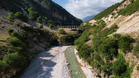 river valley and ancient aqueduct surrounded by rocky mountain and lush vegetation in albania