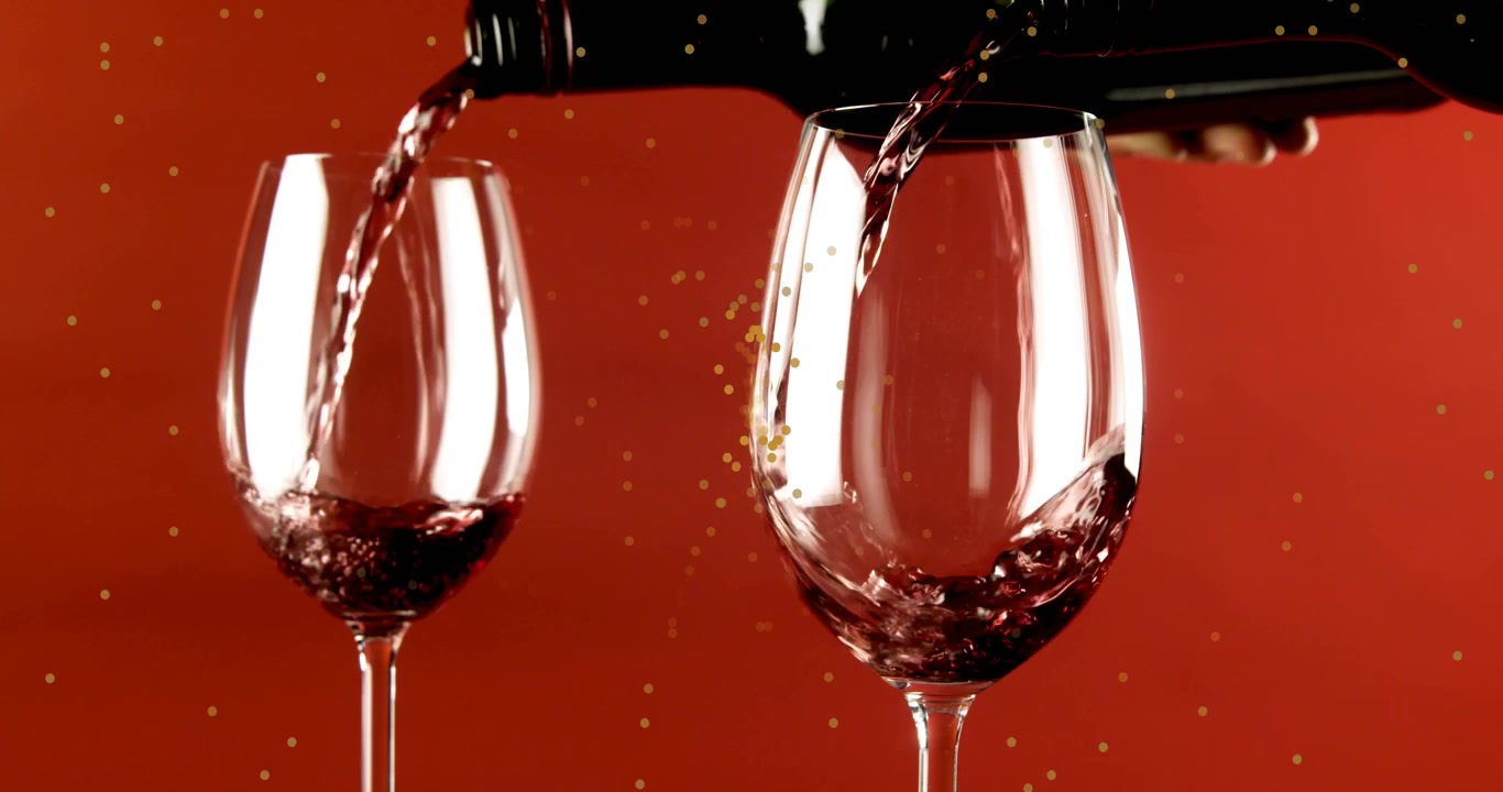 Animação de pontos amarelos em movimento sobre vinho tinto sendo derramado em taças, em fundo vermelho.