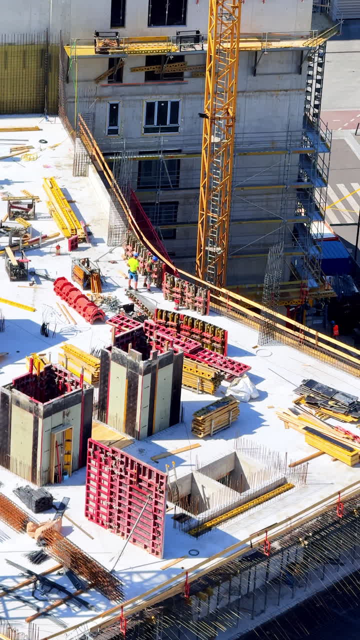Sunny day at construction site. Workers are actively constructing a building at a construction site with equipment and materials scattered around