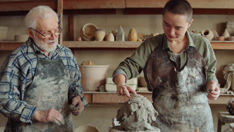 young woman learning clay sculpting with senior potter