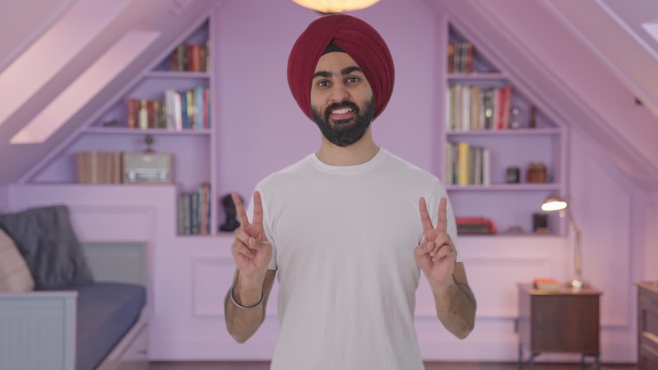 Uomo indiano Sikh felice che mostra il segno della vittoria