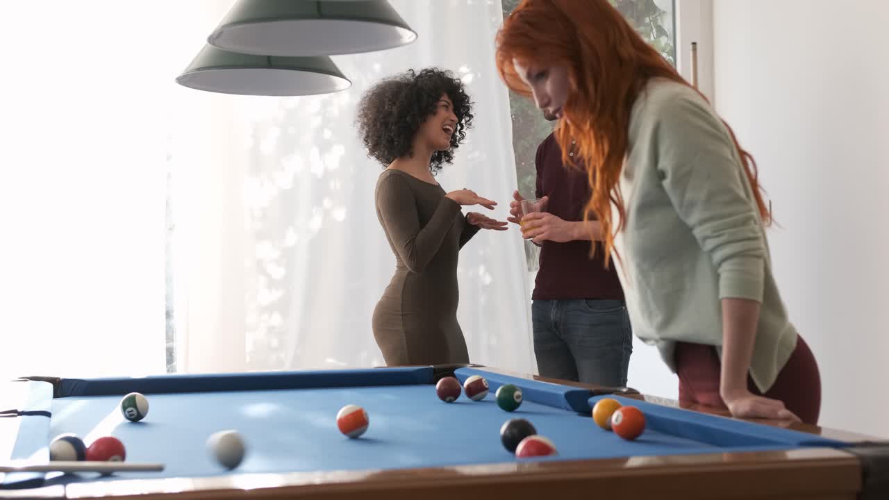 Friends talking near pool table in game room at home