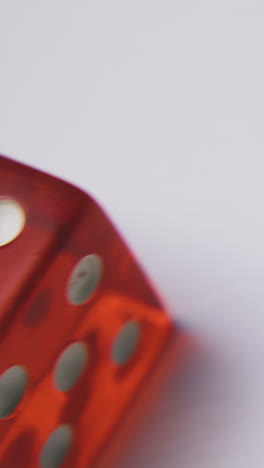motion above red plastic dices with spots on transparent sides on white surface extreme close view