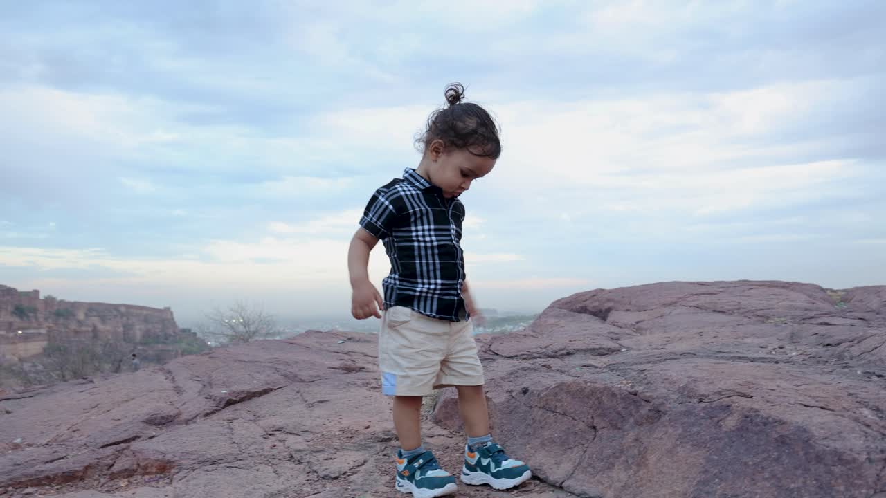 고립 된 유아가 저녁에 산의 바위에서 고 있습니다.