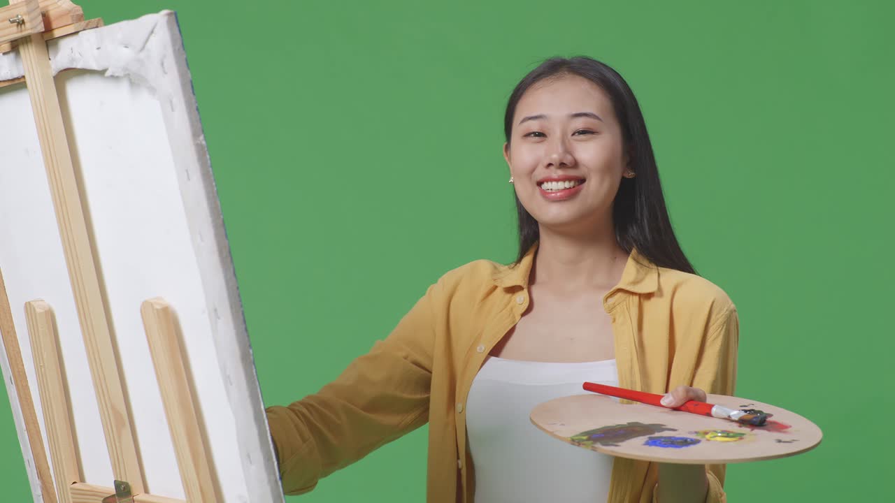 페인팅 도구 와 캔버스 를 가지고 포즈 를 취하는 여성 예술가