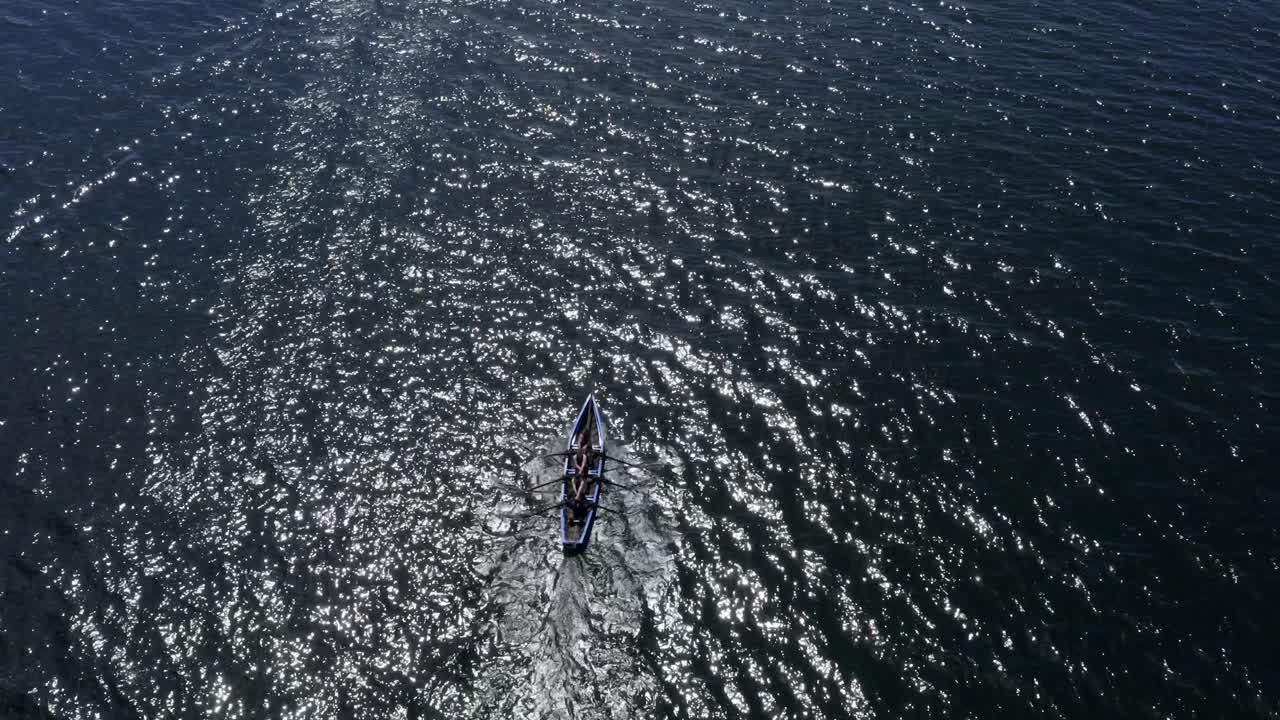 Glistening open ocean water and currach racers paddle rowing creating a wake