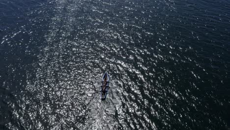 glistening open ocean water and currach racers paddle rowing creating a wake