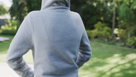 vista trasera de una mujer con capucha blanca en un jardín soleado en cámara lenta con espacio de copia