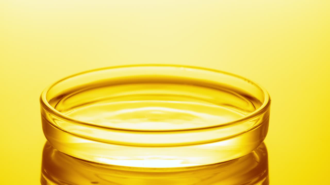 물방울이 파동을 일으키는 액체와 함께 페트리 접시에 떨어집니다.