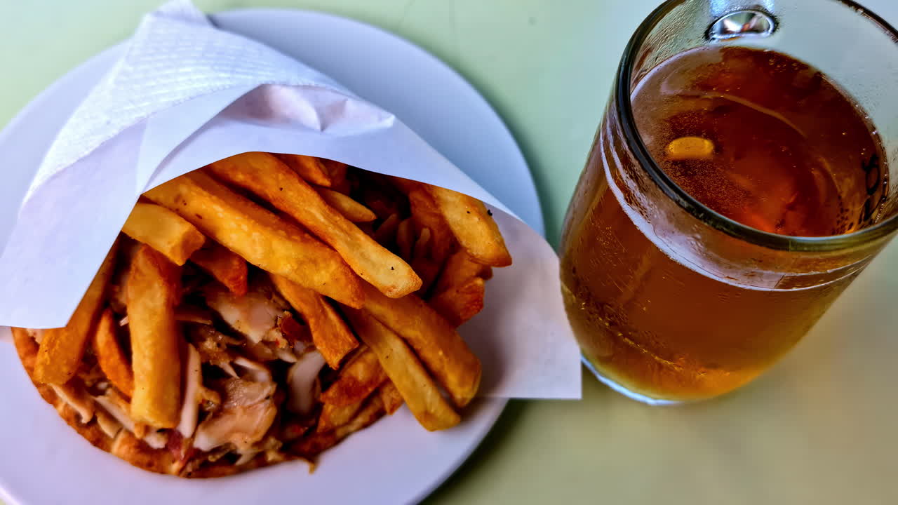Close-up of a Greek lunch with fried potatoes and a refreshing beverage, served outdoors at a local Crete café