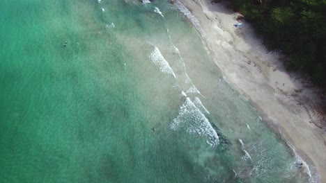 Turquoise-Blue-Ocean-With-Swimmers-Near-Sandy-Costa-Rica-Cahuita-Beach-Shore,-4K-Drone