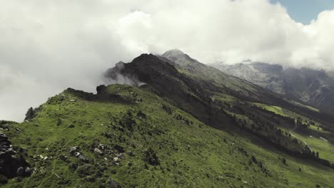 Aerial-drone-shot-of-a-grass-covered-mountain-top-with-a-small-trail-leading-along