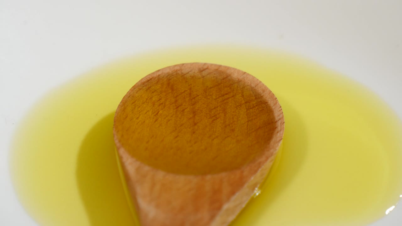 Olive oil with wood spoon in rotation