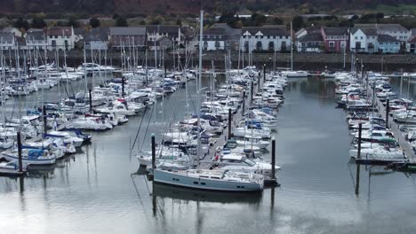 Scenic-luxurious-waterfront-harbour-apartment-village-yachts-and-sailboats-under-mountain-coastline-low-right-dolly-aerial-view