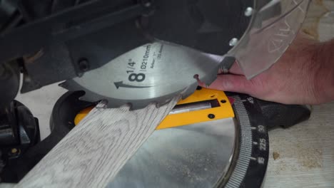 man cutting laminate floor plank with electrical circular saw