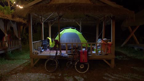 carpa iluminada montada sobre una estructura de cabaña de madera por la noche