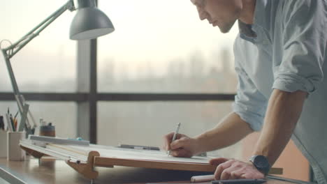 um arquiteto masculino cria um desenho de um edifício em papel. para estudar o projeto de instalações para criar móveis e casas. grande escritório moderno desenha em quadro preto.