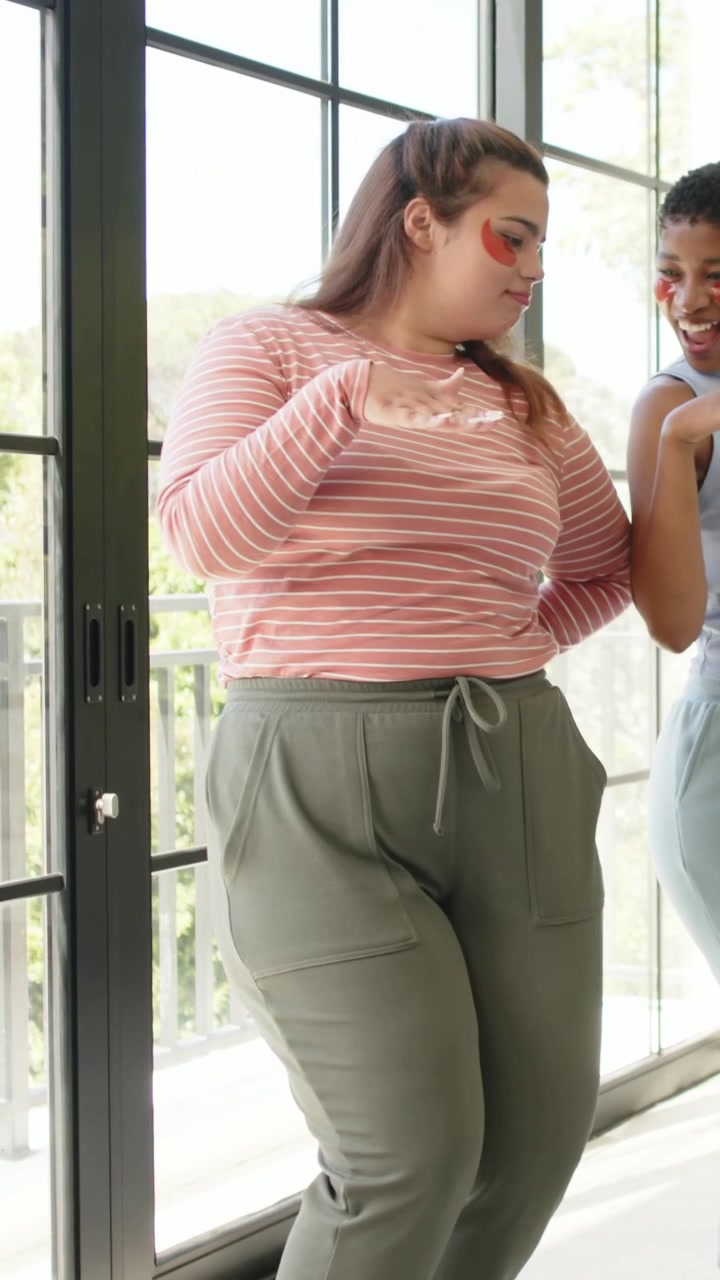 Video verticale: Donna con top a righe si gira mentre cammina, un'amica entra da porte a vetri; pittura facciale.