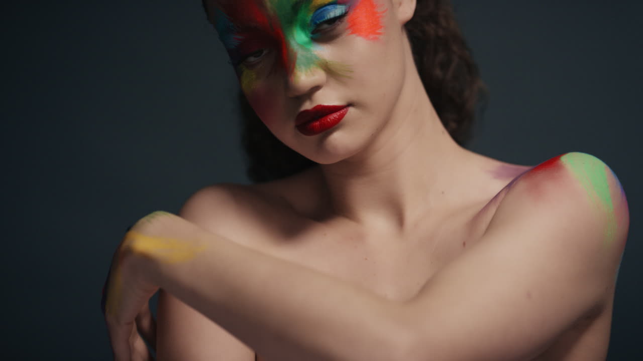 retrato de cerca mujer atractiva con cara pintada de colores exótico arte corporal multicolor sensual mujer que disfruta de la expresión creativa