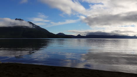 La-Primera-Luz-Del-Amanecer-Besa-Suavemente-El-Cristalino-Lago-Shikotsu,-Mientras-Las-Exuberantes-Montañas-Verdes-Se-Alzan,-Pintando-La-Serena-Obra-Maestra-De-La-Naturaleza.