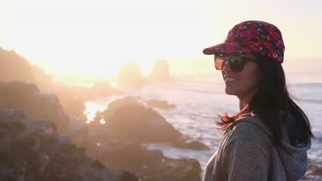 woman from back watching the sunset with the sun in the sea on surf beach in punta de lobos