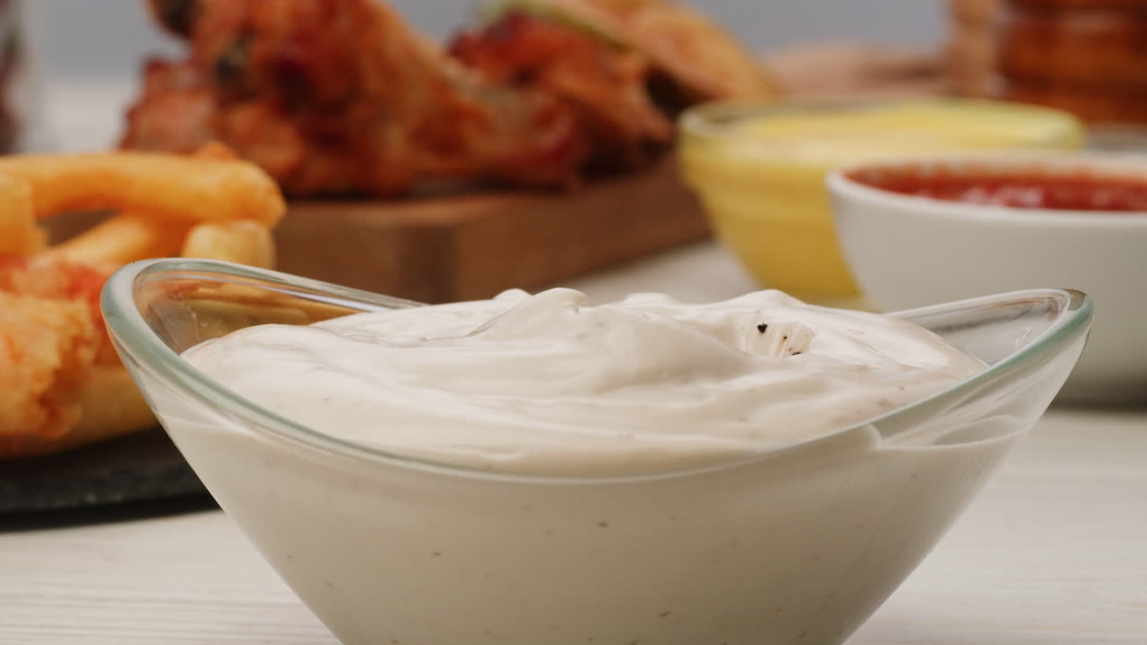 Dipping grilled meat into creamy sauce with side of fries and chicken wings