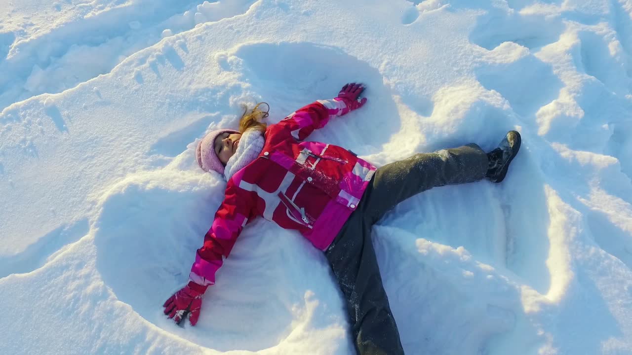 niño haciendo ángel de nieve. hermosa niña jugando en la nieve