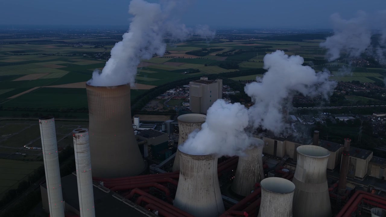 Vista aerea della centrale elettrica di Niederausem in Germania al tramonto, che mostra una massiccia centrale a combustibili fossili con torri di raffreddamento fumanti e infrastrutture energetiche industriali